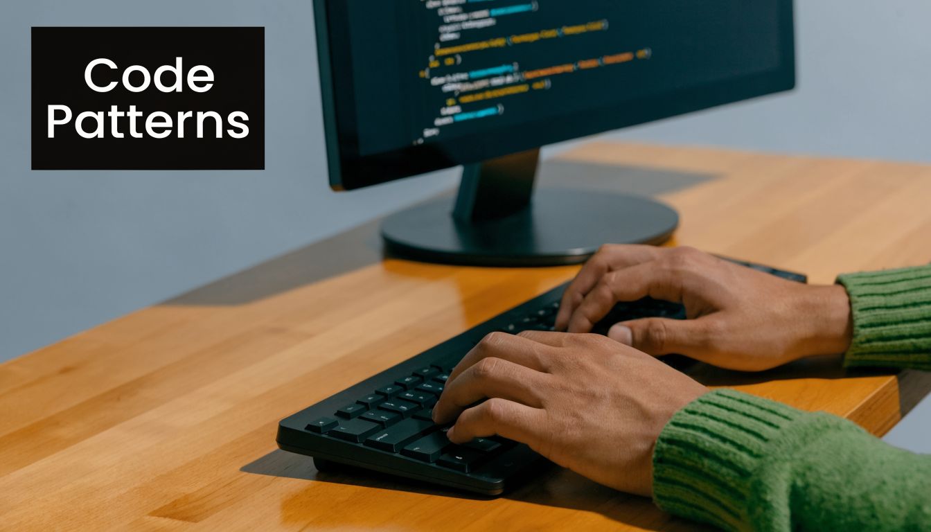 A programmer typing code on a black computer keyboard at a wooden desk with a monitor.